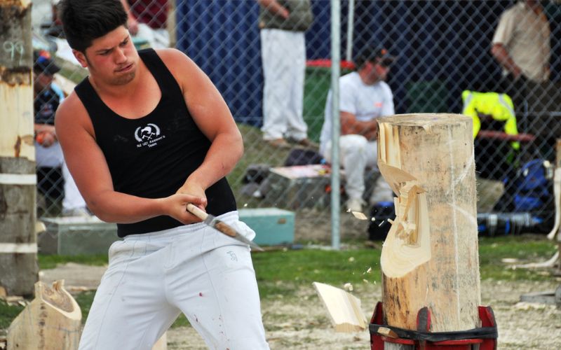man in black singlet chopping wood at competition